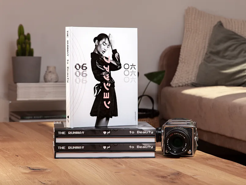 PDP | Bildband | Product Selector Section (US, BE, IT, ES, EU) | Media #2 | Image Coffee table books stacked on top of each other on a living room table, with a camera next to them