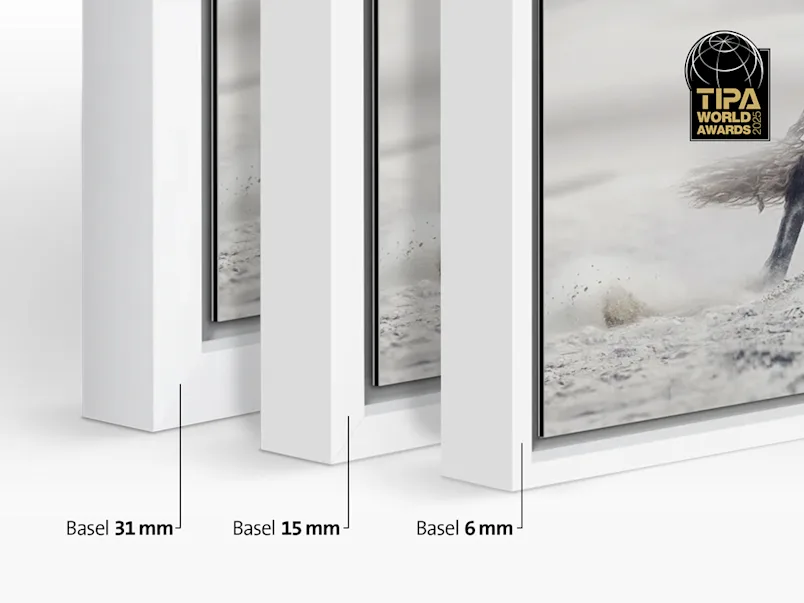 Close-up of three frame profiles standing next to each other. From left to right: Basel 1.22 in., Basel 0.59. in. and the new profile Basel 0.24 in. Several different motifs framed in a Floater Frame hang on a wall in a living room.