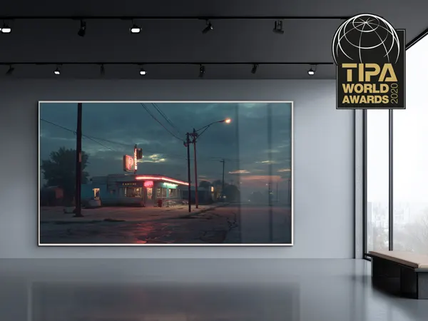 Best Photo Lab - TIPA 2020 Framed twilight photograph of a gas station with red neon lights displayed in a modern gallery space with TIPA World Awards logo