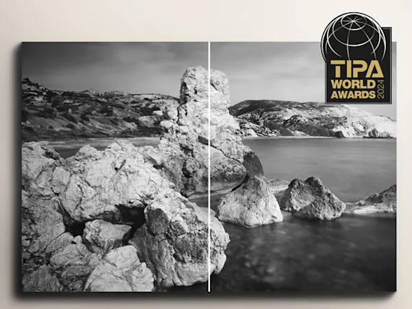 Best Photo Lab - TIPA 2024 Black and white coastal landscape with rugged rock formations jutting from calm waters, with TIPA World Awards logo overlay