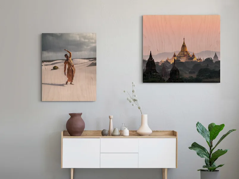 PDP | Direct Print on Wood | Product Selector Section | Media #3 Two motifs on Direct Print On Wood on a wall in a living room. One with a person stands in front of sand dunes in a desert and one with a temple in the sunset.