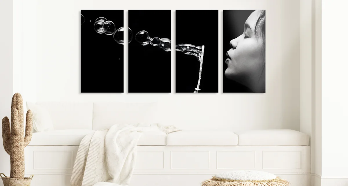 PDP | Multi Panel Wall Art | Big Picture Slider Section > Four-piece | Slide #1 | Media #1 A woman is blowing soap bubbles. The whole picture is divided into four parts hanging horizontally on the wall.